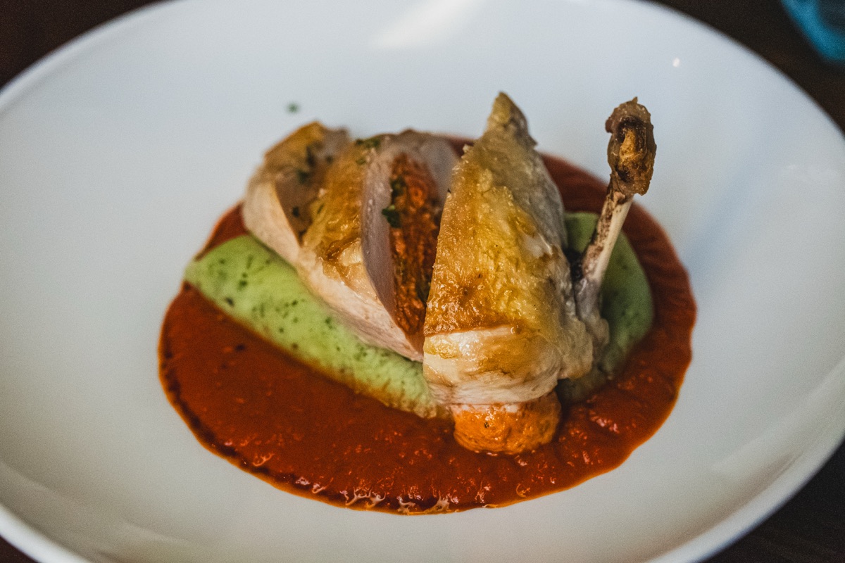 Roast chicken supreme on crushed minted peas with red pepper sauce